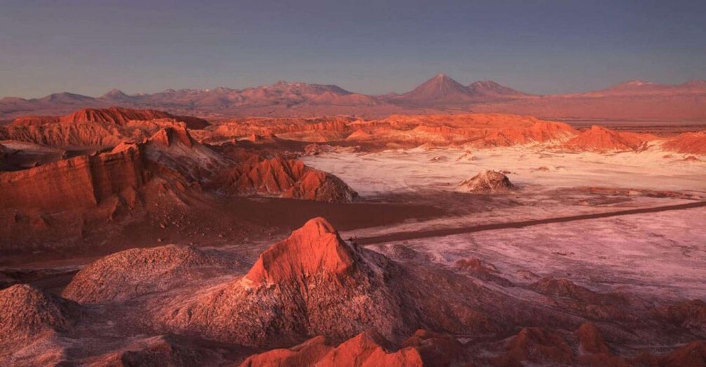 Paisaje desértico con formaciones rocosas rojas destacadas y montañas lejanas bajo un cielo despejado. 2