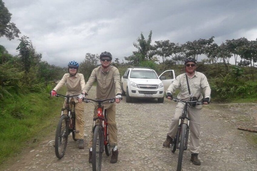 Three cyclists on a gravel path with a car parked in the background. 3