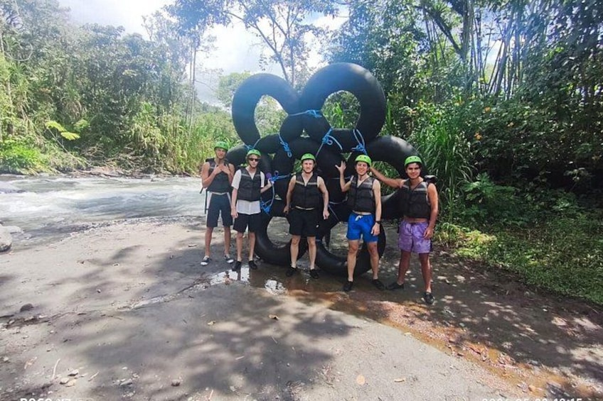 A group of people standing in front of a large black inflatable structure in a forested area. 1