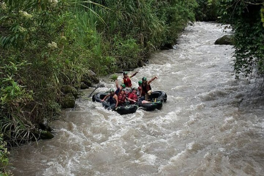 A group of people rafting down a river surrounded by dense vegetation. 5