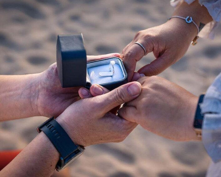 A person holding a black box with a ring inside, another person receiving it. 5