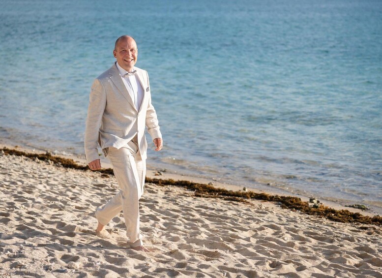 A person walking on a sandy beach with calm water in the background. 4