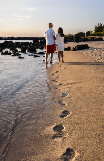 A couple walking on a sandy beach with footprints leading into the water. 1