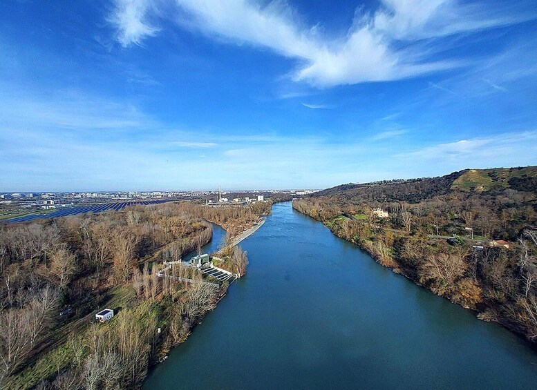 A river flowing through a valley with a bridge, surrounded by hills and sparse trees. 2
