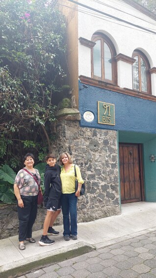 Three people standing in front of a building with a sign that reads '91 BIS'. 1