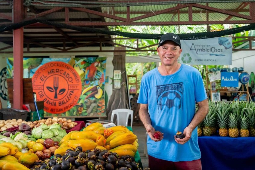 A person at a market stall with various fruits and vegetables on display. 5