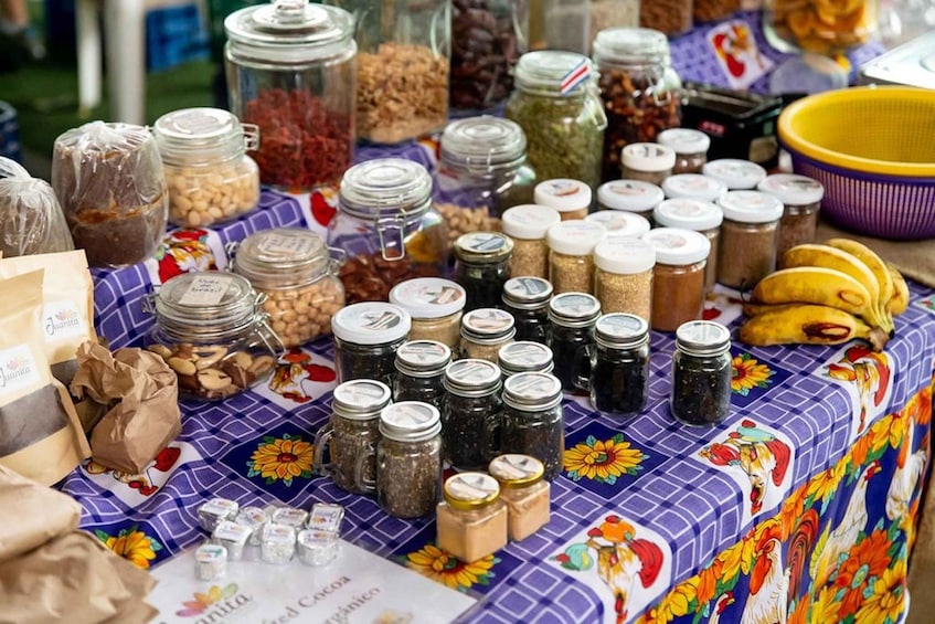 A table with various jars of spices and grains, a banana, and a purple bowl. 1