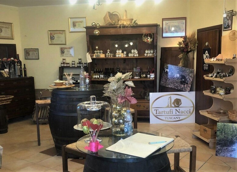 A bar area with a sign for 'Tartufi Nacci Tuscany,' featuring a rustic interior with wooden shelves, a bar counter, and various bottles. 2