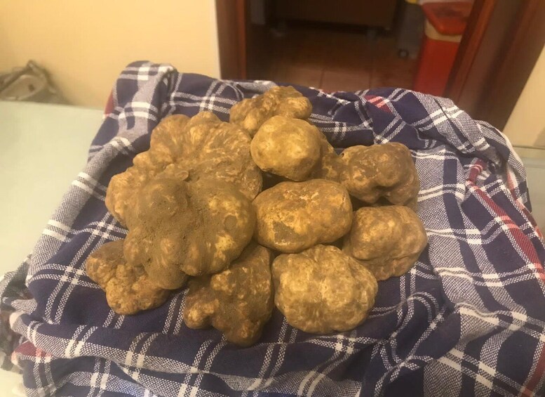 A pile of golden-brown potatoes on a plaid cloth. 1