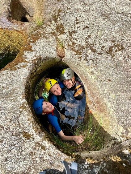 Three people inside a cave with a helmeted individual in the center. 2