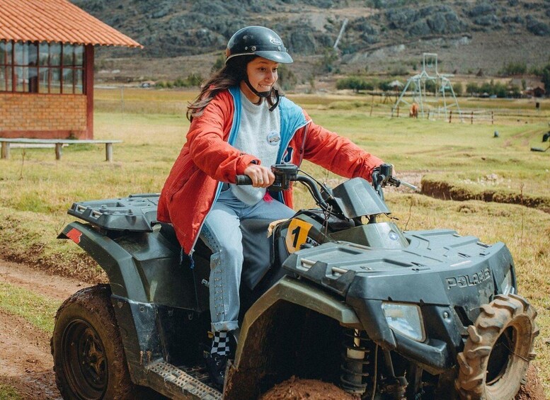 A person riding a Polaris ATV on a dirt path with a rural landscape in the background. 1