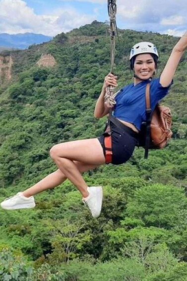 A person zip-lining through a lush green forest with mountains in the background. 3