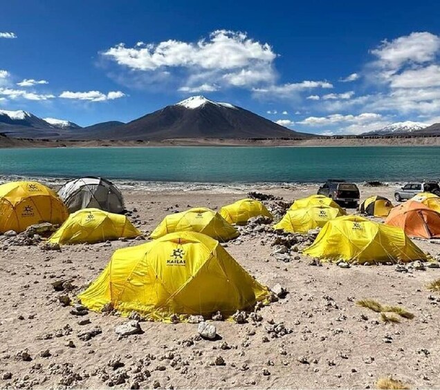 Yellow tents on a rocky beach with a mountain in the background. 1