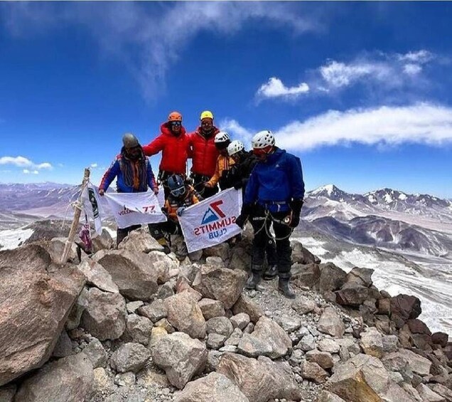 A group of climbers on a rocky mountain peak with a clear sky. 2