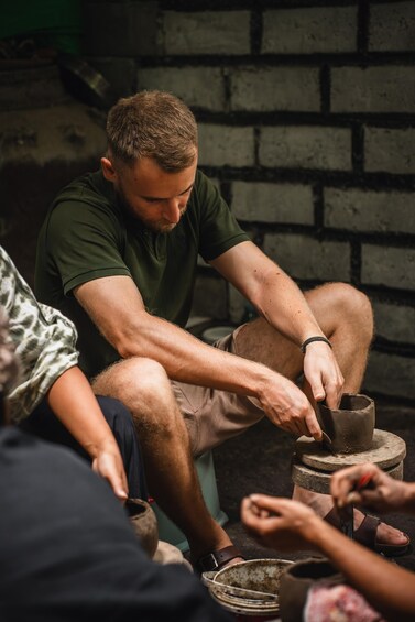 A person crafting pottery on a wheel in a workshop with brick walls. 1