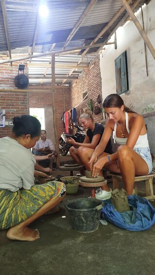 A group of people engaged in pottery making, with clay wheels and pottery tools visible. 5