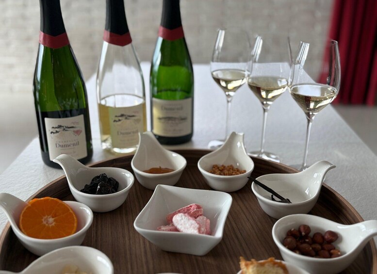 A tasting tray with wine bottles and glasses, and small bowls containing various food items. 1