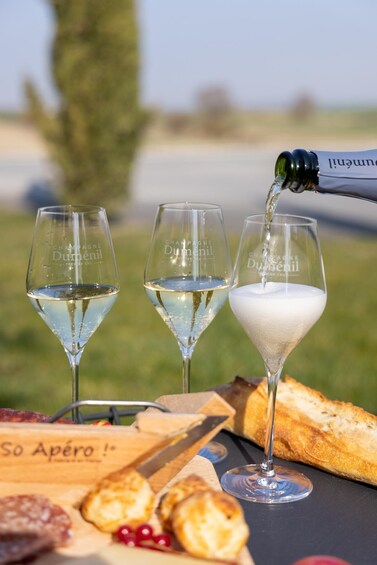 Three champagne glasses on a table with a bottle being poured into one. 5