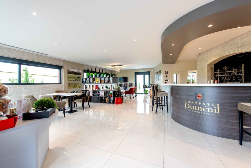 A modern bar area with a curved counter, a selection of bottles, and a seating arrangement. 4