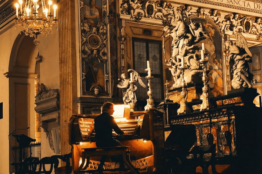 Una persona suona un pianoforte a coda in una stanza riccamente decorata, con sculture elaborate e un lampadario. 3
