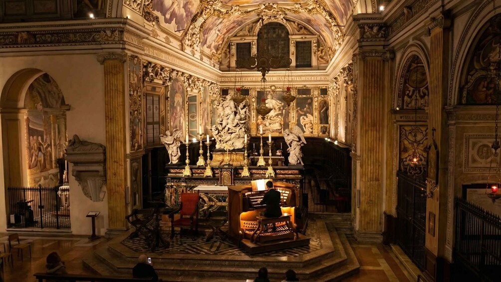 Interno di una chiesa decorata, con un altare centrale, statue e elaborate decorazioni al soffitto. 1