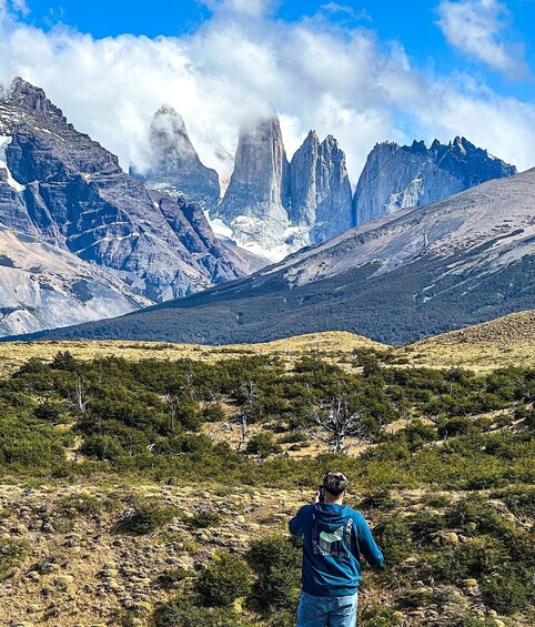 A person standing on a hill with a mountainous landscape in the background. 4