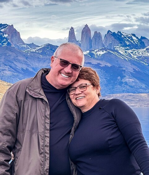 A couple standing in front of a mountainous landscape with snow-capped peaks. 2