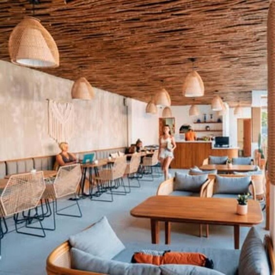 An indoor café with wooden furniture, woven chairs, and pendant lighting. 2