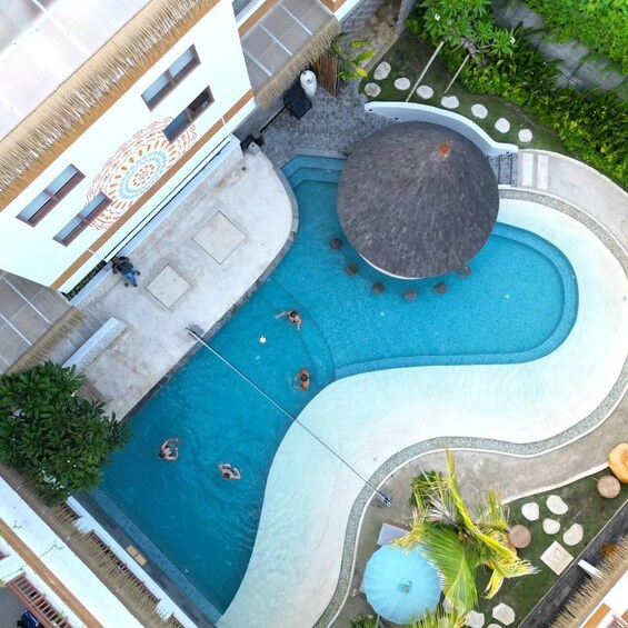 An aerial view of a swimming pool with a unique design, surrounded by greenery and a building with a decorative facade. 4