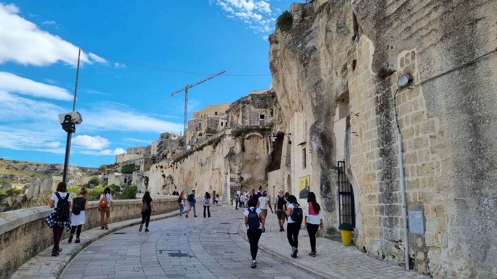 A stone pathway with people walking, a construction crane, and old buildings. 2