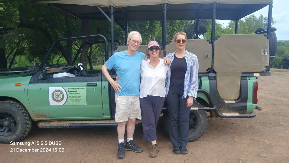 Three people standing in front of a green safari vehicle with a Bushbaby Safari Zululand logo. 4