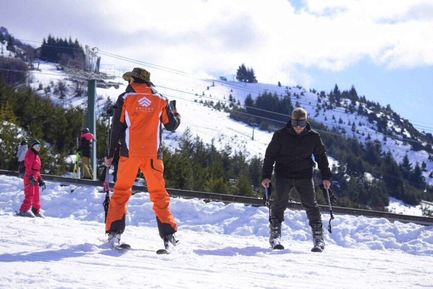 Skiers on a snowy slope with a ski lift in the background. 1