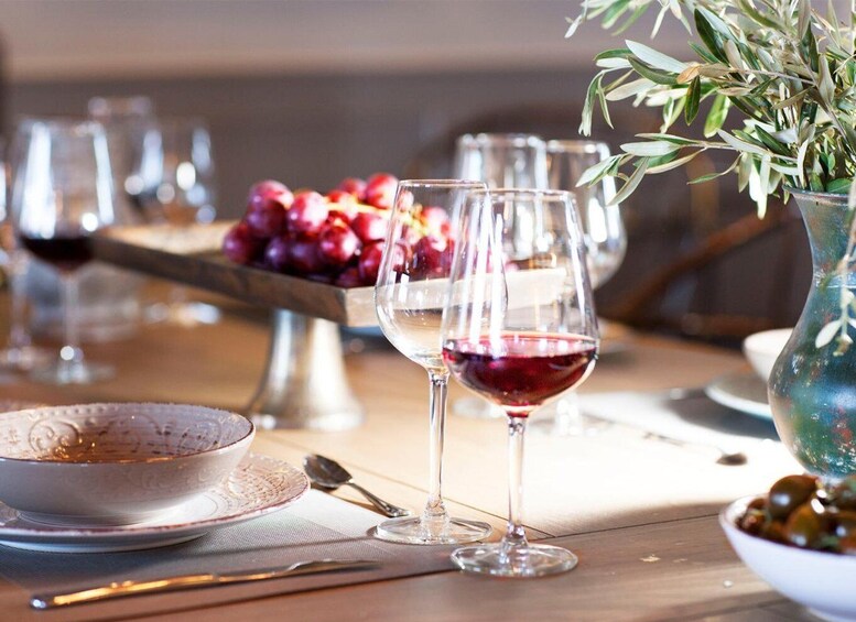 A dining table with wine glasses, a bowl of olives, and a vase with greenery. 2