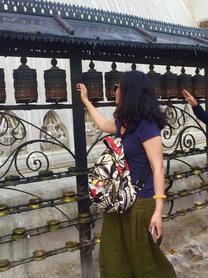 A person standing in front of a traditional structure with metal railings and decorative elements. 2