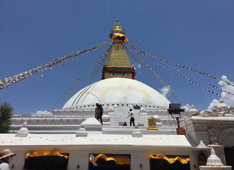 A large white dome with a golden spire, surrounded by colorful prayer flags. 1