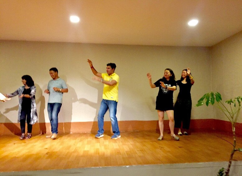 A group of people performing on a wooden stage with a plant in the background. 5