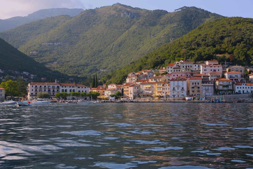 A coastal town with buildings along the waterfront, boats docked, and mountains in the background. 2