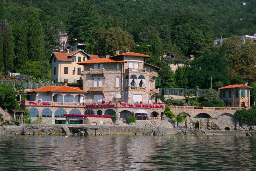 A waterfront property with multiple buildings, a stone bridge, and lush greenery. 5