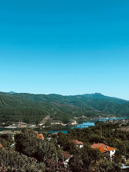 A mountainous landscape with a lake, houses, and a clear blue sky. 2