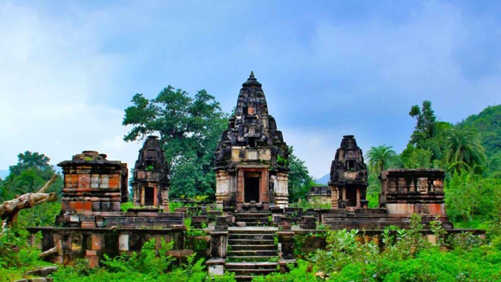 An ancient temple complex with multiple structures, surrounded by lush greenery and trees. 3