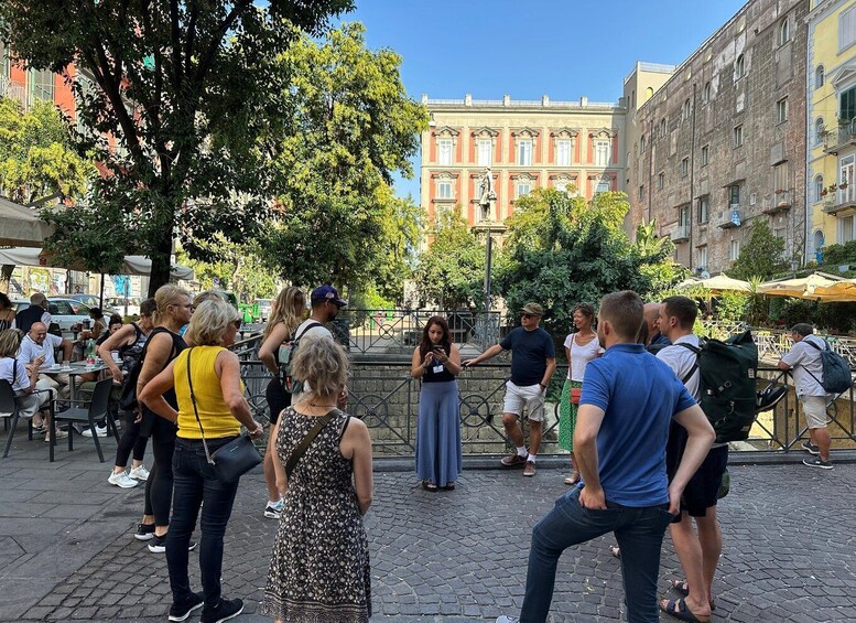 A group of people standing in a plaza with buildings in the background. 2