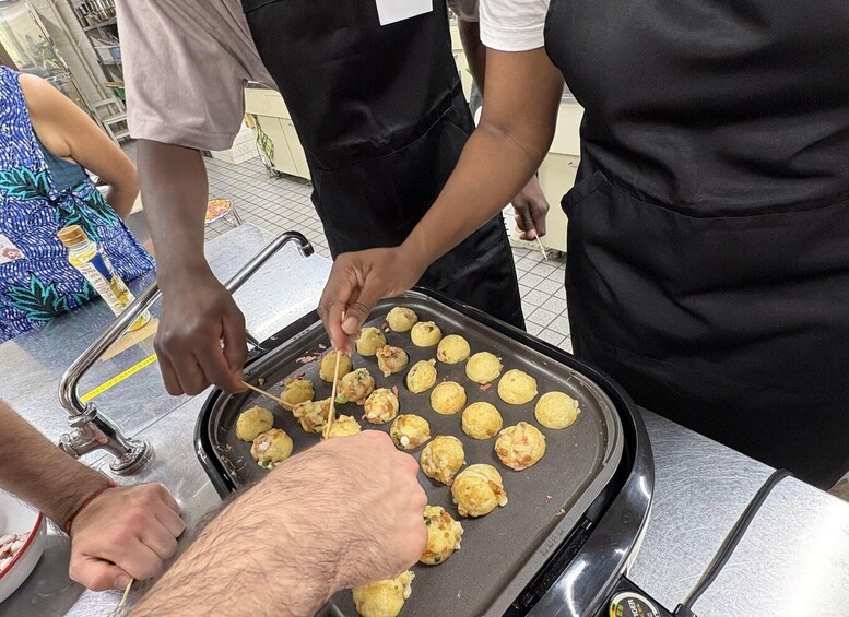 People cooking on a grill with dough balls. 2