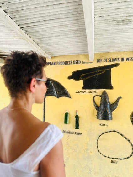 A person standing indoors with a yellow wall displaying items like a Canon gun, a Kettle, and a Bead. 5
