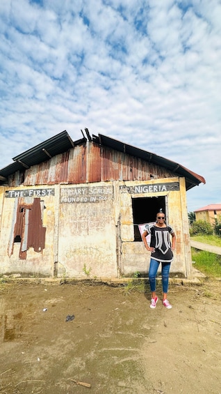 A dilapidated school building with a corrugated metal roof and a sign that reads 'The First Primary School Founded in 184'. 4