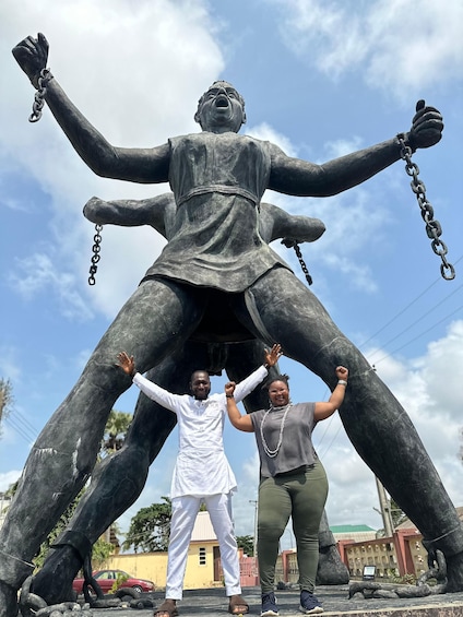 A large statue with multiple arms and chains, with two people standing in front of it. 3