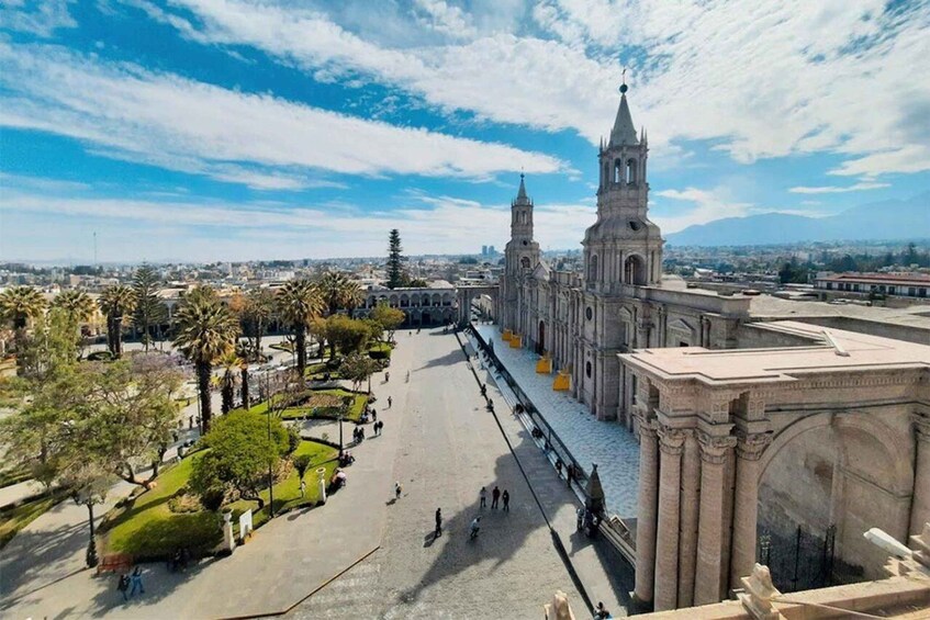 A historic cathedral with twin towers, a plaza with people, and a cityscape in the background. 3