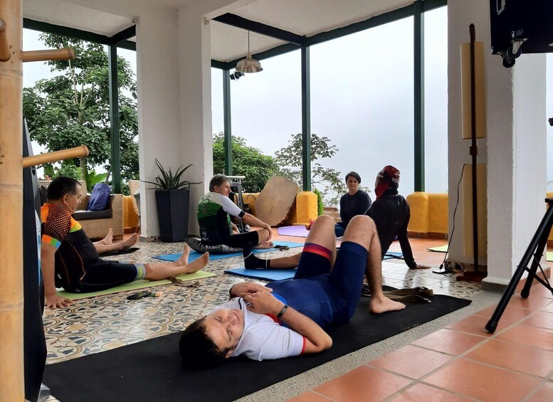 A group of people practicing yoga on mats in a room with large windows and a tiled floor. 2