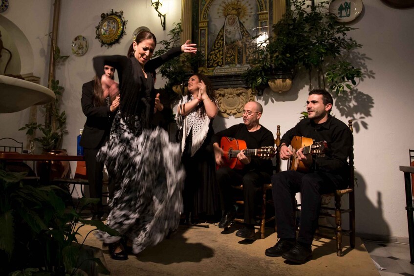 A group of people performing music in a room with religious artwork and plants. 1