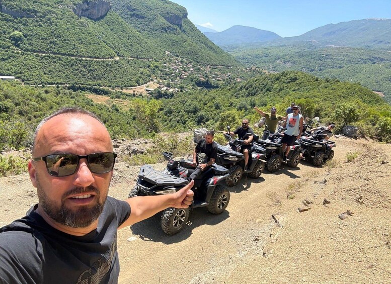A group of people on ATVs on a dirt path with a mountainous landscape in the background. 5