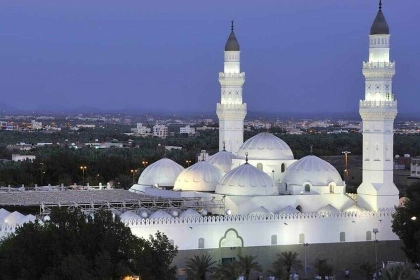 A mosque with multiple domes and minarets, surrounded by a cityscape at dusk. 1